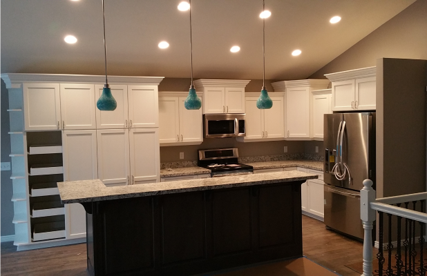 Fully restored and modernized kitchen featuring white cabinetry, granite countertops, stainless steel appliances, and pendant lighting.
